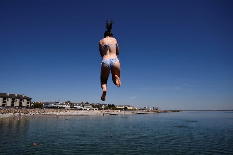 FILE PHOTO: A woman jumps from a diving board into the sea on Salthill beach during sunny weather in Galway