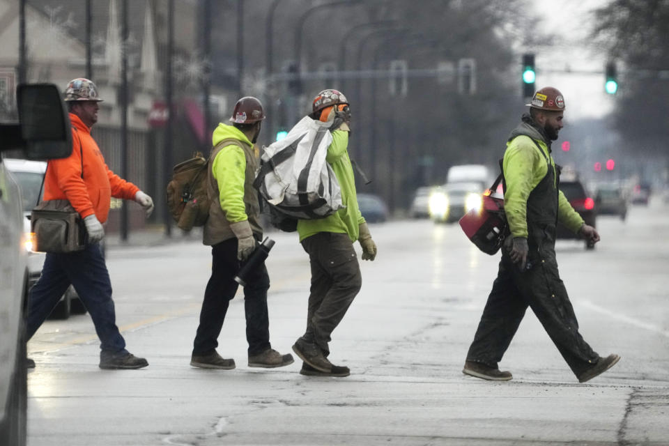 Construction workers cross a street in Wilmette, Ill., Thursday, Jan. 5, 2023. America’s employers added a solid 223,000 jobs in December, evidence that the economy remains healthy yet also a sign that the Federal Reserve may still have to raise interest rates aggressively to slow growth and cool inflation. (AP Photo/Nam Y. Huh)