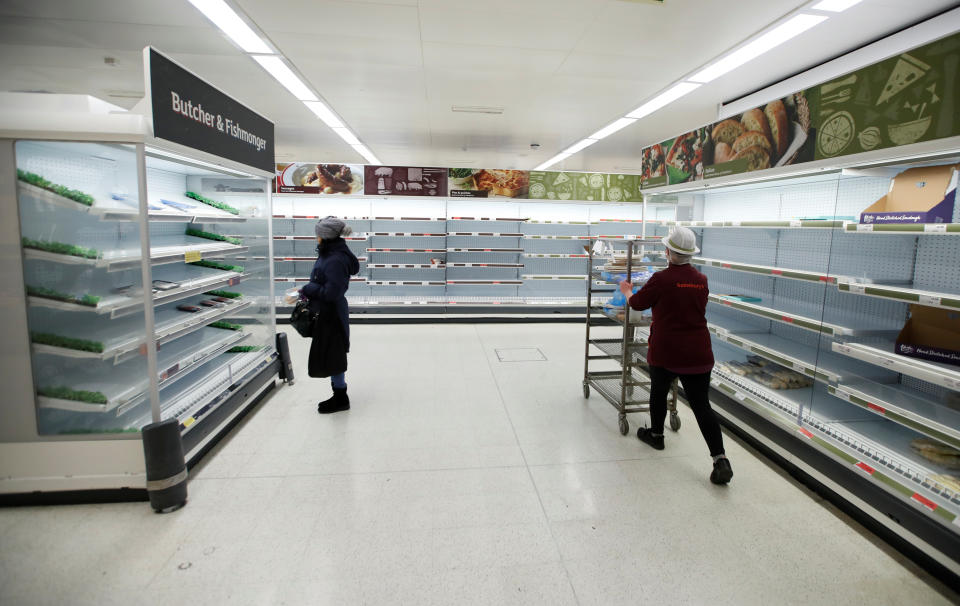 A Sainsbury's worker walks past a customer next to empty shelves at a Sainsbury's store in Harpenden as the spread of the coronavirus disease (COVID-19) continues, in Harpenden, Britain, March 18, 2020. REUTERS/Peter Cziborra