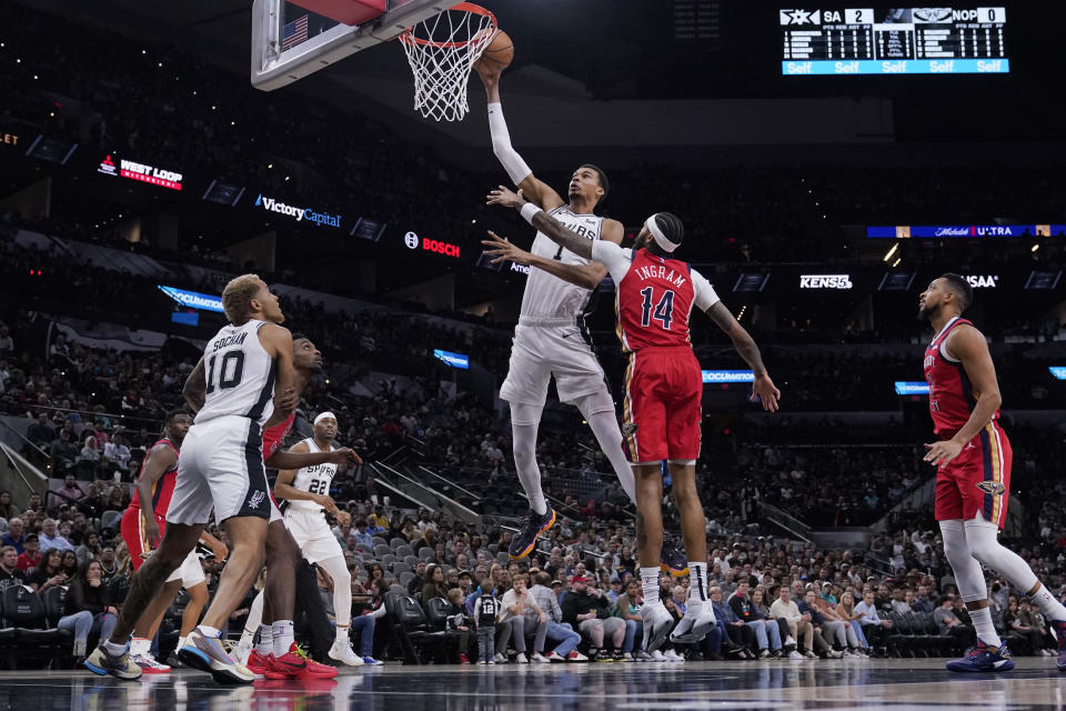 San Antonio Spurs center Victor Wembanyama (1) scores past New Orleans Pelicans forward Brandon Ingram (14) during the first half of an NBA basketball game in San Antonio, Sunday, Dec. 17, 2023. (AP Photo/Eric Gay)