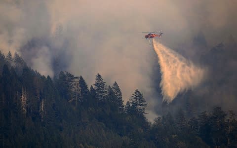 A helitanker drops water on Mt St Helena  - Credit: The Press Democrat via AP