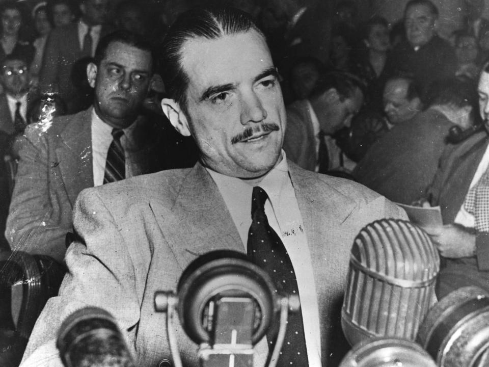 Howard Hughes sitting at a bank of microphones, multi-millionaire, aviator, film producer and director in 1947.