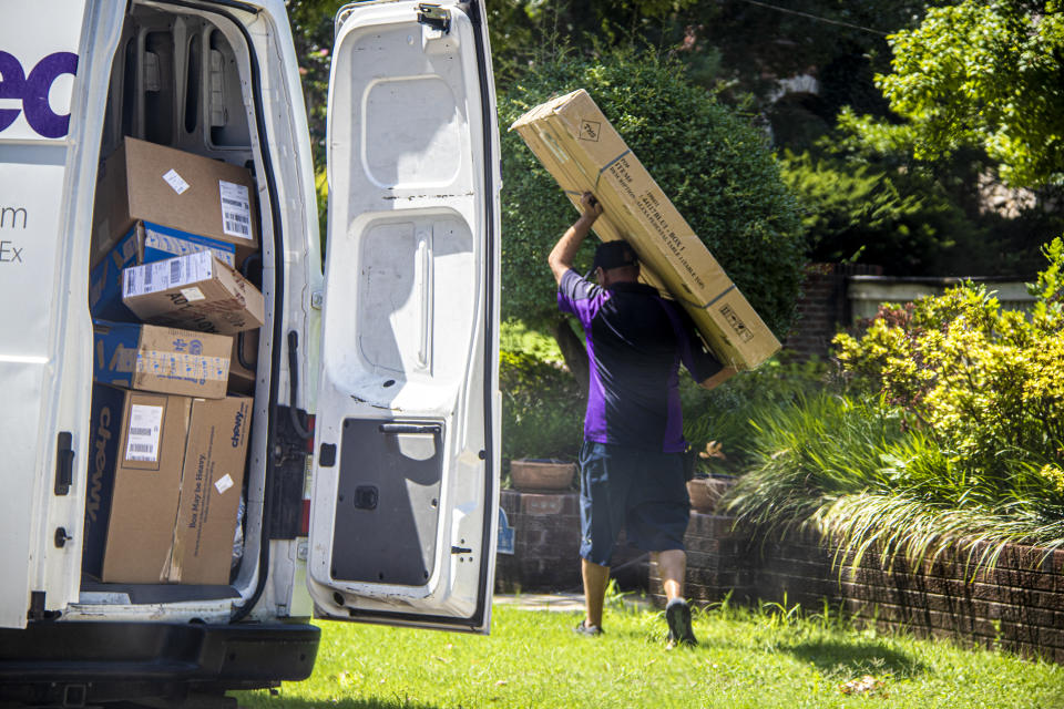 07-14-2020 Tulsa USA Delivery man carries large box above head with back door to van open showing many more boxes in leafy neighborhood