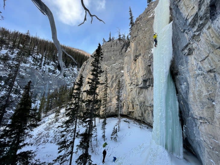 Climber top ropes vertical pitch of ice.