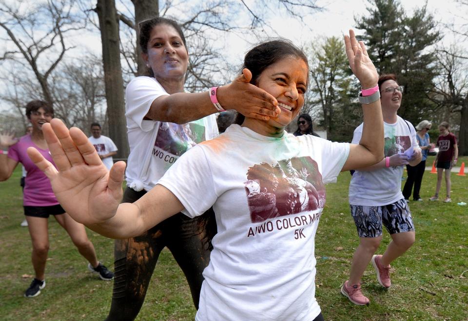 Reshma Patel of Springfield, front, gets orange powder smeared on her face by her sister-in-law Ramya Patel, also of Springfield, during the celebration of Holi at Washington Park Saturday April 23, 2022.
