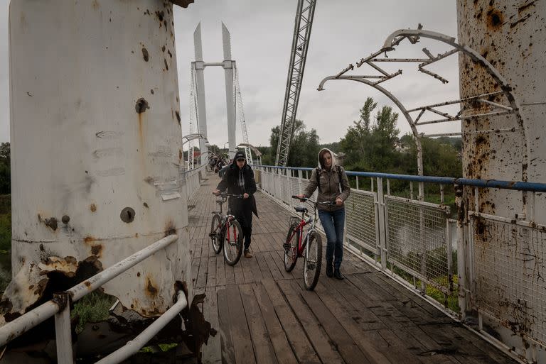 Residentes cruzan un puente atacado en la ciudad Izium el 14 de septiembre. (Nicole Tung/The New York Times)