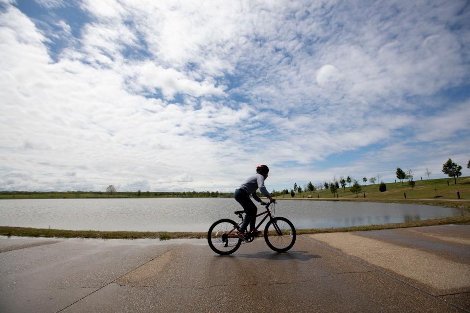 A boy rides his bicycle around Hyde Lake on Tuesday, March 31, 2020, at Shelby Farms Park in Memphis.