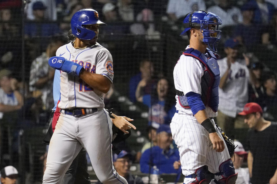 New York Mets' Francisco Lindor, left, scores on a throwing error by Chicago Cubs relief pitcher Daniel Norris as catcher Yan Gomes looks to the field during the 10th inning in the second baseball game of a doubleheader in Chicago, Saturday, July 16, 2022. (AP Photo/Nam Y. Huh)