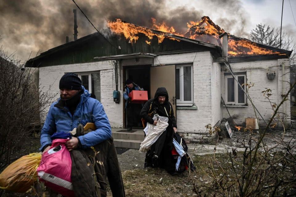 Personas sacan sus pertenencias de una casa en llamas luego de un bombardeo en la ciudad de Irpin, en las afueras de Kyiv (AFP/Getty)
