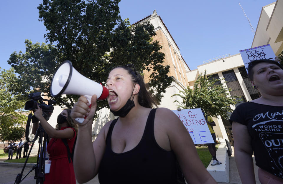 Raynie Castaneda leads a chant against Texas Gov. Greg Abbott across the street from the building where he signed Senate Bill 1, also known as the election integrity bill, into law in Tyler, Texas, Tuesday, Sept. 7, 2021. The sweeping bill signed by the two-term Republican governor further tightens Texas' strict voting laws. (AP Photo/LM Otero)