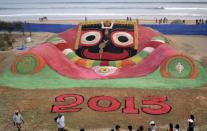 Visitors look at a sand sculpture designed to celebrate the 2013 new year by sand artist Sudarshan Pattnaik on the beach in Puri, about 65km (40 miles) from the eastern city Bhubaneswar in the Indian state of Odisha December 31, 2012.