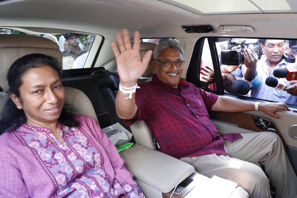 Sri Lanka's former Defense Secretary and presidential candidate Gotabaya Rajapaksa, right, waves to the media as he leaves with his wife Ayoma after casting vote in Embuldeniya, on the outskirts of Colombo, Sri Lanka, Saturday, Nov. 16, 2019. Polls opened in Sri Lanka’s presidential election Saturday after weeks of campaigning that largely focused on national security and religious extremism in the backdrop of the deadly Islamic State-inspired suicide bomb attacks on Easter Sunday. (AP Photo/Eranga Jayawardena)