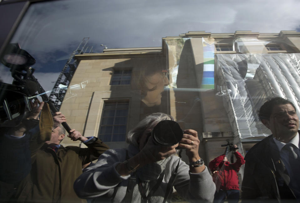 FILE - Journalists, including Associated Press photographer Anja Niedringhaus, reflected in the window at lower center, surround the car of Bouthaina Shaaban, advisor to Syrian President Assad, as she leaves after meeting with the Syrian opposition at the United Nations headquarters in Geneva, Switzerland, Switzerland, Monday, Jan. 27, 2014. On April 4, 2014, outside a heavily guarded government compound in eastern Afghanistan, Niedringhaus was killed by an Afghan police officer as she sat in her car. She was 48 years old. (AP Photo/Anja Niedringhaus, File)