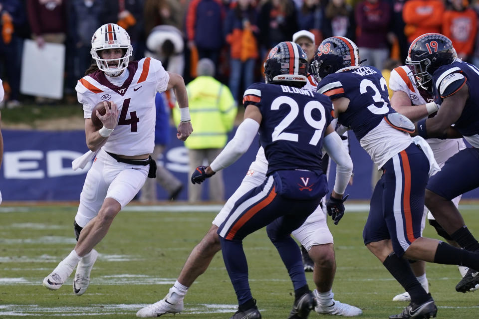 Virginia Tech quarterback Connor Blumrick (4) looks to run as Virginia free safety Joey Blount (29) and Virginia inside linebacker West Weeks (33) close in during the first half of an NCAA college football game Saturday Nov 27, 2021, in Charlottesville, Va. (AP Photo/Steve Helber)