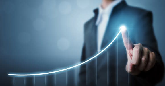 A businessman points to a chart of rising returns.