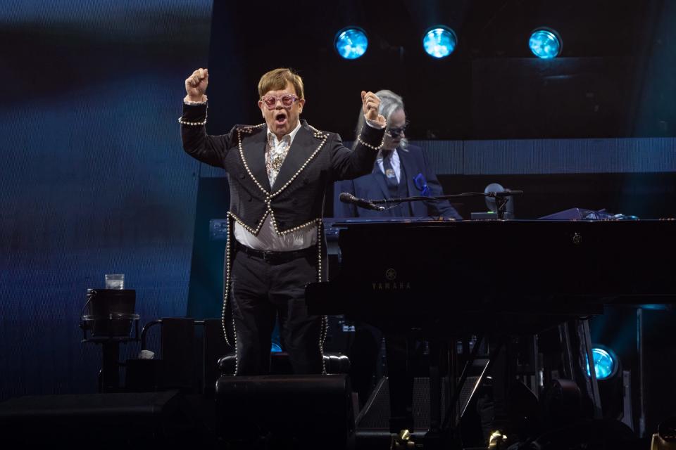 Elton John waves to the crowd between songs, with keyboardist Kim Bullard in the background, at the Alamodome in San Antonio on Saturday, Oct. 29, 2022.