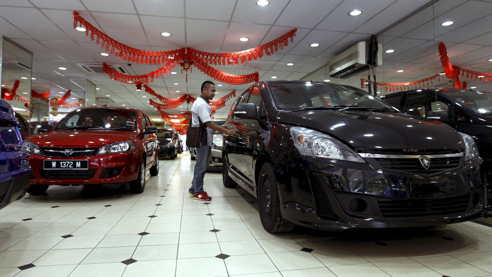 A man looks at a new car at a car showroom in Kuala Lumpur, Malaysia, Monday, Jan. 20, 2014. Malaysia's government unveiled Monday a new auto policy, offering incentives and easing curbs on the production of small, energy-efficient cars as it vies for investment with neighboring rivals Thailand and Indonesia. (AP Photo/Daniel Chan)