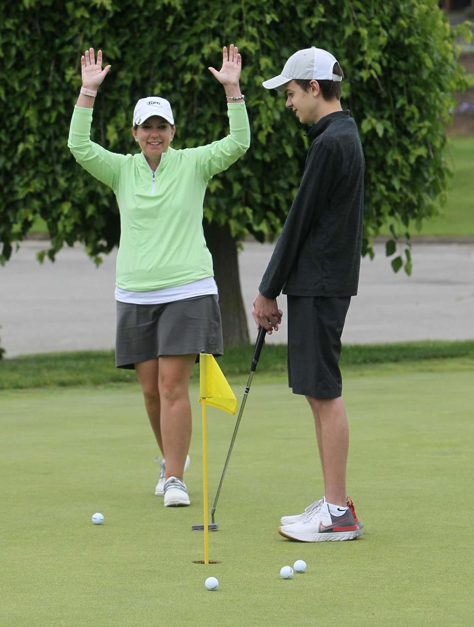 Huston Nagy, 16, right, of North Olmsted, smiles as his coach Erin Craig reacts to him sinking a putt on the putting green at Firestone Country Club on Monday in Akron.