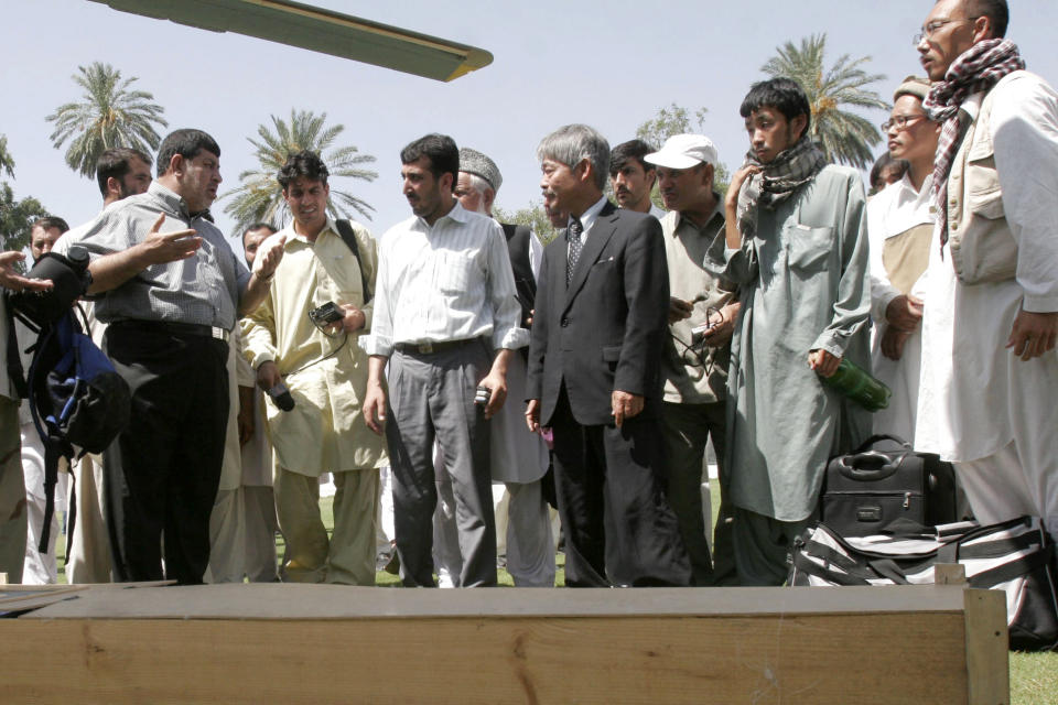 FILE -In this, Aug 28, 2008, photo, Tetsu Nakamura, center right, executive director of PMS Japan, with others, stands near the dead body of Japanese aid worker Kazuya Ito at the governor house of Jalalabad, east of Kabul, Afghanistan. The Japanese physician and aid worker in eastern Afghanistan died of his wounds after an attack Wednesday, Dec. 4, 2019, that also killed five Afghans, including the doctor’s bodyguards, the driver and a passenger, a hospital spokesman said.(AP Photo/Rahmat Gul, File)