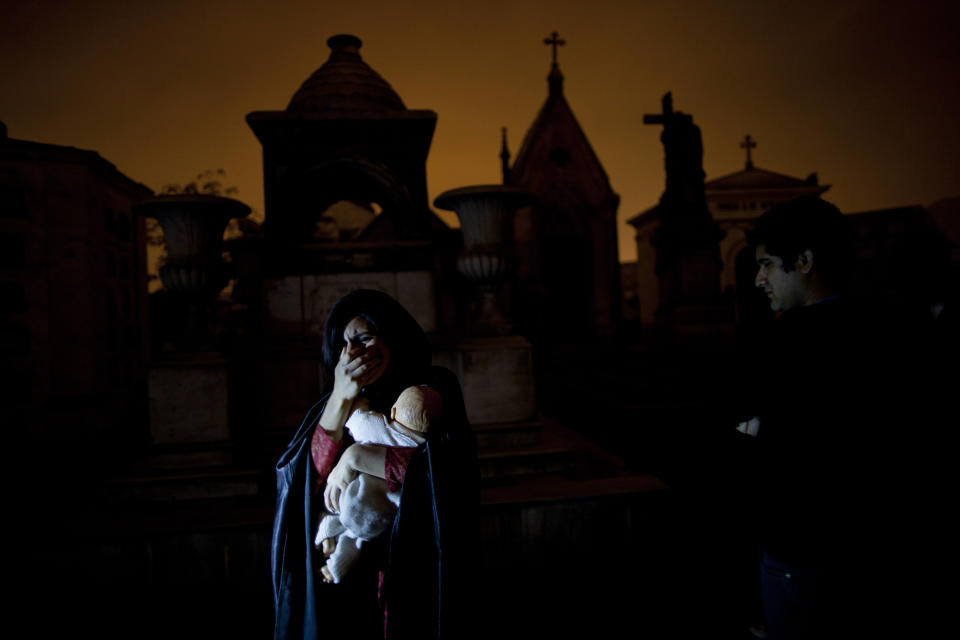 In this Nov.10, 2012 photo, a woman dramatizes a historic event during a nighttime guided tour through the Presbitero Matias Maestro cemetery in Lima, Peru. When Presbitero Matias Maestro cemetery in Lima received its first body in 1808, the best plots went to the elite, unless the noble had been dishonored or disgraced. (AP Photo/Rodrigo Abd)