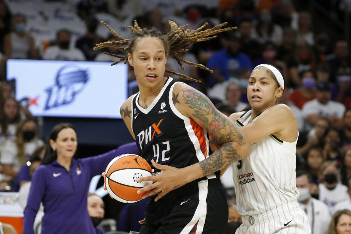 Phoenix Mercury center Brittney Griner, holding the ball and with dreadlocks flying, slams past Candace Parker, who is straining, in vain, to stop her.