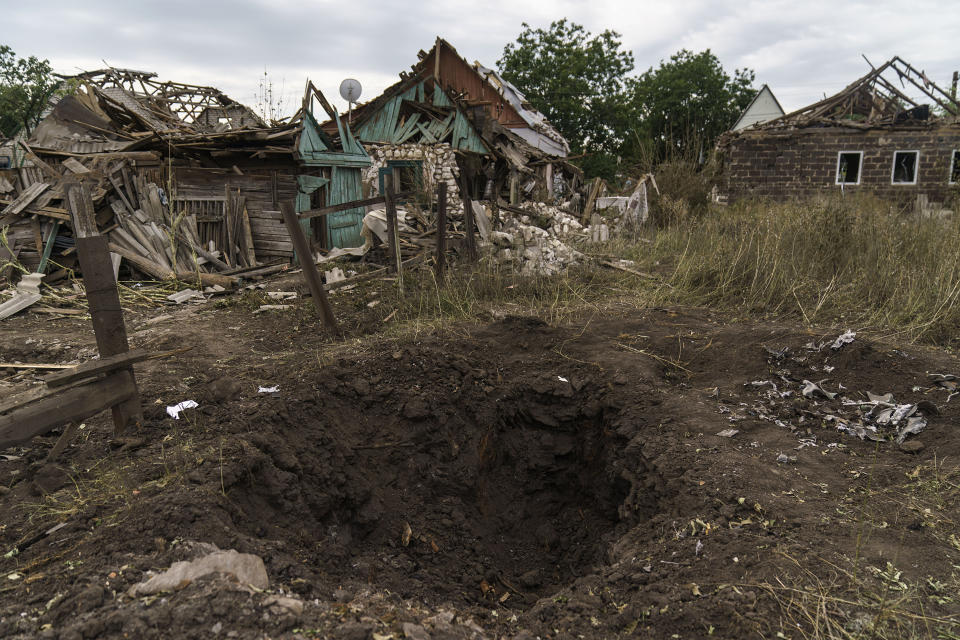 A crater from a Russian rocket attack is seen next to damaged homes in Kramatorsk, Donetsk region, eastern Ukraine, Saturday, Aug. 13, 2022. The strike killed three people and wounded 13 others, according to the mayor. The attack came less than a day after 11 other rockets were fired at the city, one of the two main Ukrainian-held ones in Donetsk province, the focus of an ongoing Russian offensive to capture eastern Ukraine's Donbas region. (AP Photo/David Goldman)