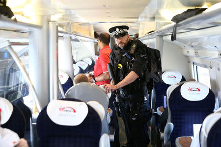 Armed police officers walk along the aisle of a train at Milton Keynes station, Britain May 25, 2017. REUTERS/Neil Hall