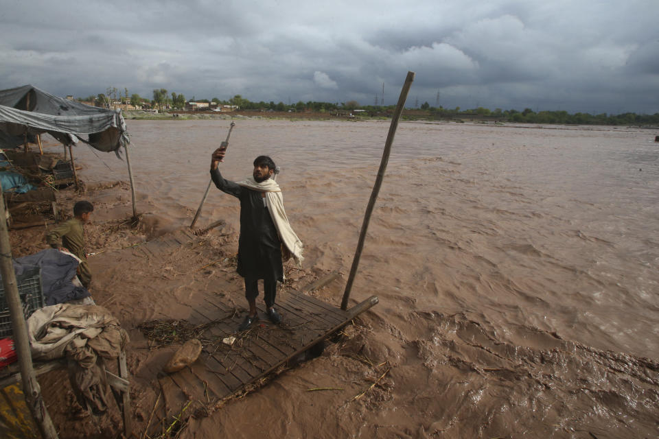 A man takes a selfie on the bank of a stream, which is overflowing following heavy rains, on the outskirts of Peshawar, Pakistan, Monday, April 15, 2024. Lightnings and heavy rains killed dozens of people, mostly farmers, across Pakistan in the past three days, officials said Monday, as authorities declared a state of emergency in the country's southwest following an overnight rainfall to avoid any further casualties and damages. (AP Photo/Muhammad Sajjad)