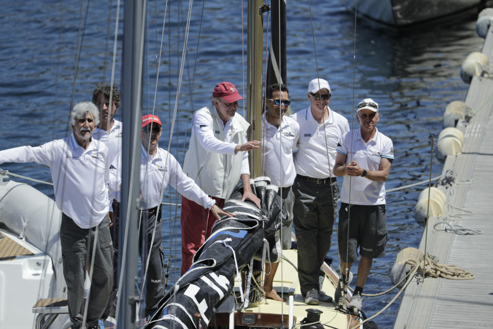 Spain's former King Juan Carlos, centre, waves next to crew members aboard the Bribon yacht before a 'regatta' race between yachts in Sanxenxo, north western Spain, Friday, May 20, 2022. Spain's former King has returned to Spain for his first visit since leaving nearly two years ago amid a cloud of financial scandals. (AP Photo/Lalo R. Villar)