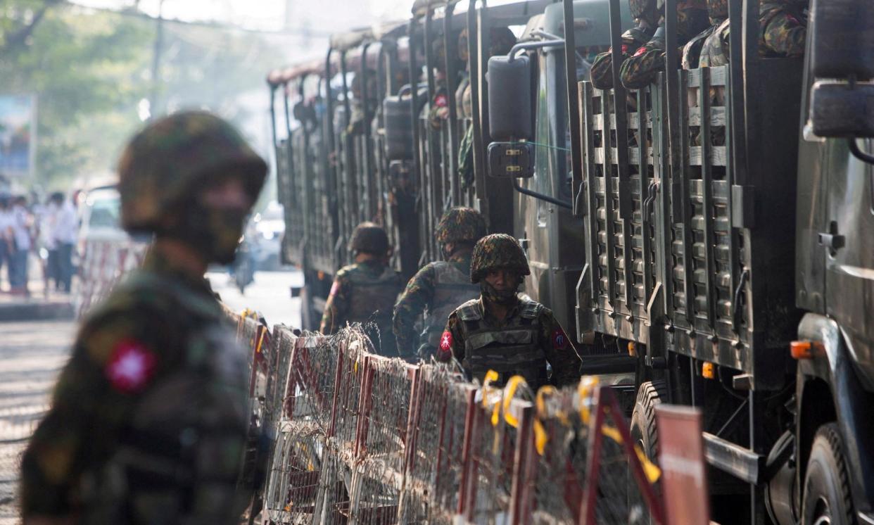 <span>Soldiers stand next to military vehicles as people gather to protest against the military coup, in Yangon, Myanmar.</span><span>Photograph: Reuters</span>