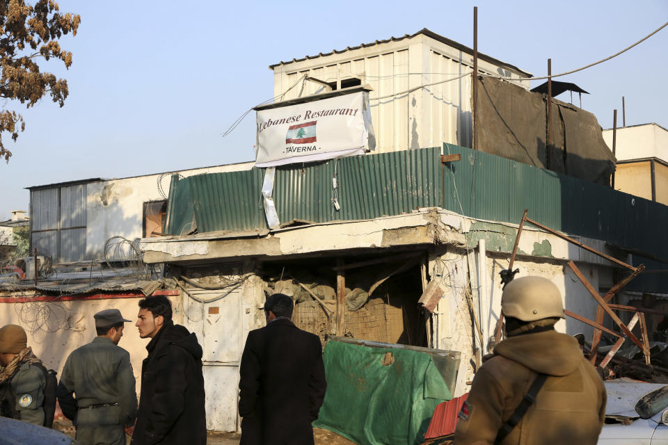 Afghan security forces investigate the aftermath of Friday's suicide attack and shooting in Kabul, Afghanistan, Saturday, Jan. 18, 2014. A suicide bomber blew himself up outside a Kabul restaurant, seen in the background, filled with foreigners and affluent Afghans, while two gunmen snuck in through the back door and opened fire Friday in a brazen dinnertime attack that killed 16 people, officials said. (AP Photo/Rahmat Gul)