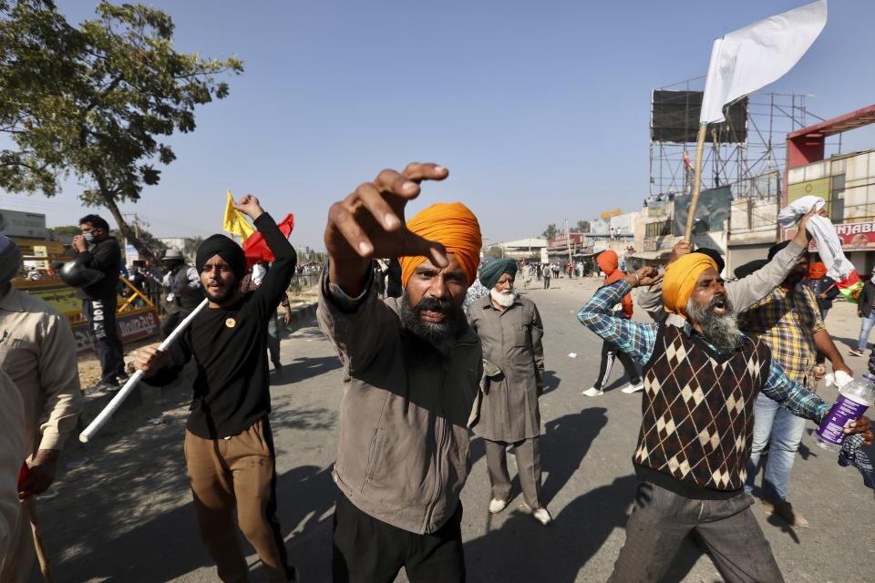 Protesting farmers shout slogans and face security officers at the border between Delhi and Haryana state, Friday, Nov. 27, 2020. Thousands of agitating farmers in India faced tear gas and baton charge from police on Friday after they resumed their march to the capital against new farming laws that they fear will give more power to corporations and reduce their earnings. While trying to march towards New Delhi, the farmers, using their tractors, cleared concrete blockades, walls of shipping containers and horizontally parked trucks after police had set them up as barricades and dug trenches on highways to block roads leading to the capital. (AP Photo/Manish Swarup)