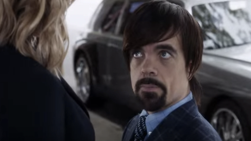 Peter Dinklage in a wig with long bangs that swoop to one side