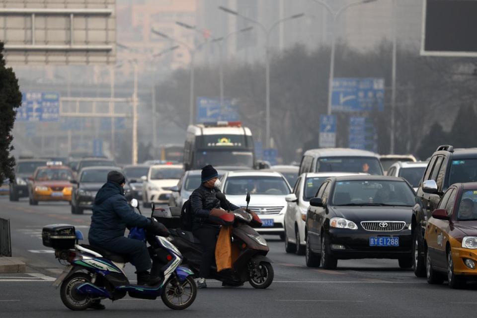 Electric bike riders wearing mask to protect themselves from exhaust gas wait at a traffic lights junction during a heavily polluted day in Beijing, Sunday, Dec. 18, 2016. China's capital and other northern cities have banned half of all vehicles from city streets and ordered factories, schools and construction sites closed in response to a five-day smog red alert. (AP Photo/Andy Wong)