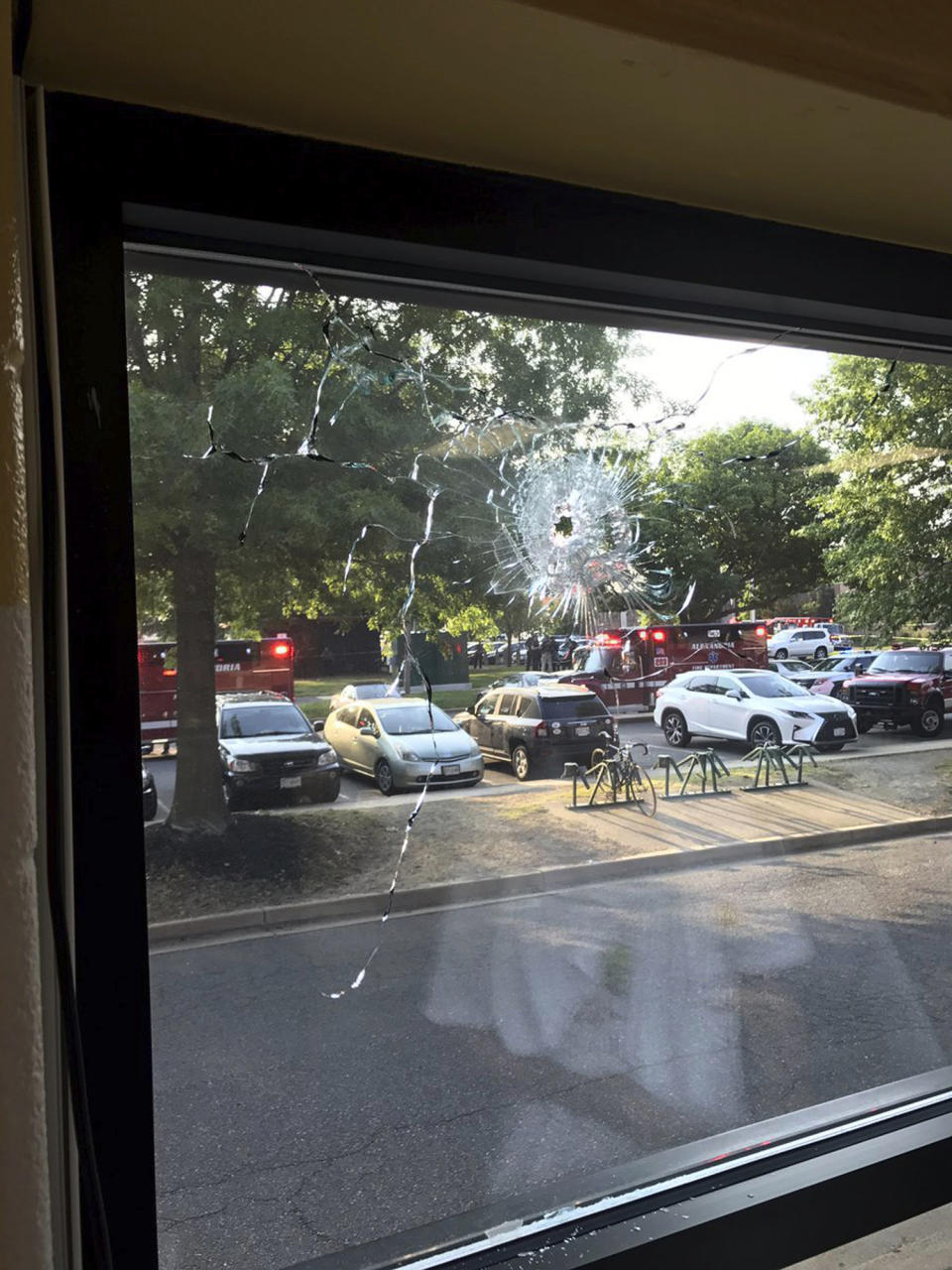 <p>Emergency personnel are seen through a window with a bullet hole in Alexandria, Va., Wednesday, June 14, 2017. House Majority Whip Steve Scalise of Louisiana and others were shot Wednesday at a congressional baseball practice, officials said. (Photo: Joseph Miscavige via AP) </p>