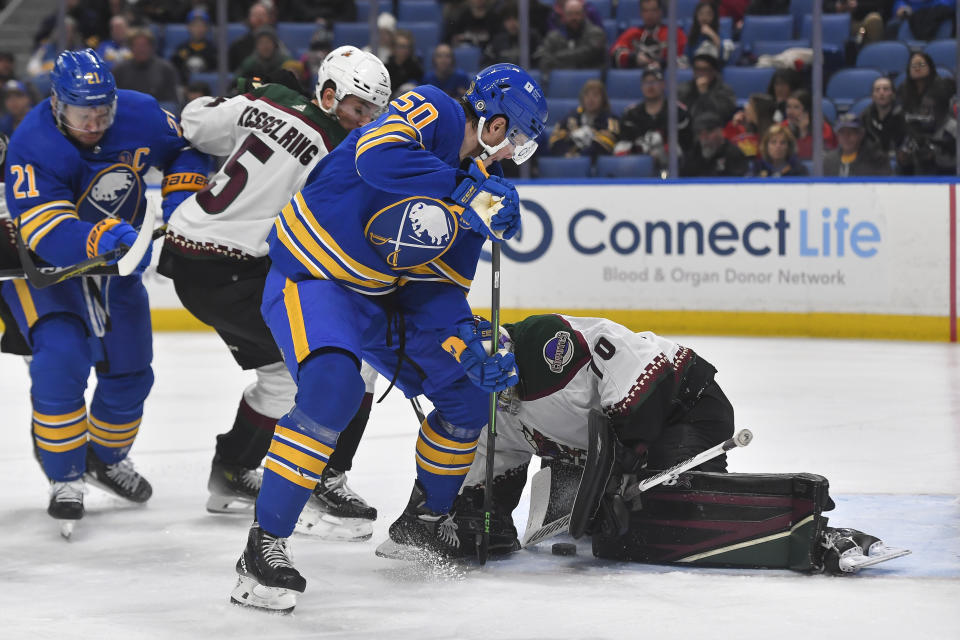 Buffalo Sabres left wing Eric Robinson (50) scores against Arizona Coyotes goalie Karel Vejmelka, right, during the second period of an NHL hockey game in Buffalo, N.Y., Monday, Dec. 11, 2023. (AP Photo/Adrian Kraus)