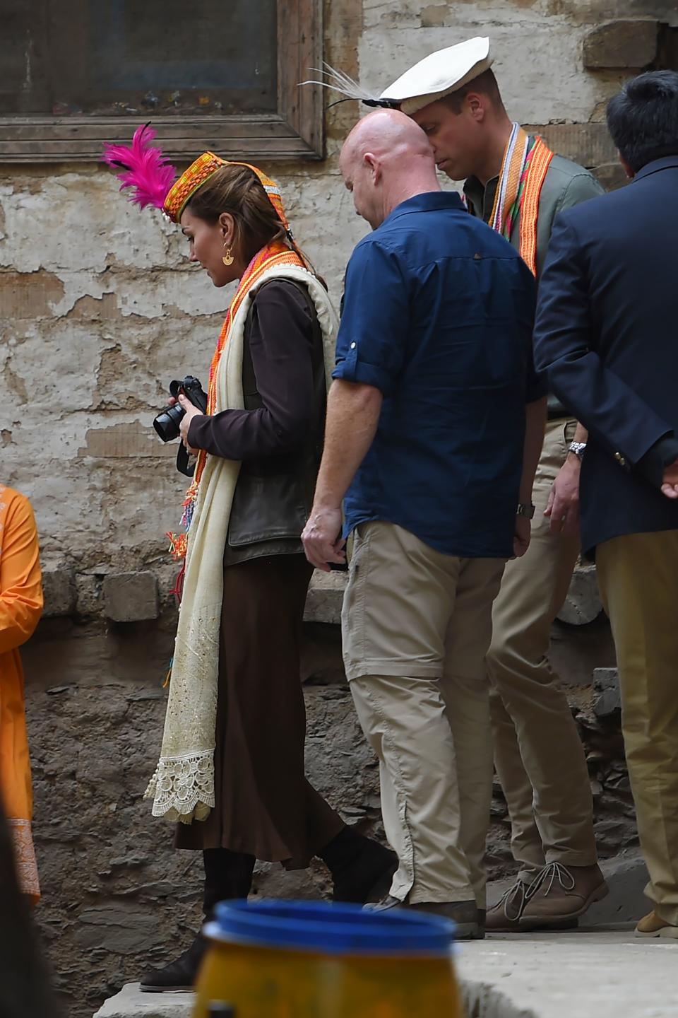 Britain's Prince William (C), Duke of Cambridge follows his wife Britain's Catherine (L), Duchess of Cambridge, as she holds a camera during their visits at the Kalash tribe village in Bumburate Valley in Pakistan northern Chitral District on October 16, 2019. - Prince William and his wife Kate flew near the Afghan border to visit a remote Hindu Kush glacier on October 16, after a morning spent trying on feathered traditional caps and luxurious shawls in Pakistan's mountainous north. (Photo by FAROOQ NAEEM / AFP) (Photo by FAROOQ NAEEM/AFP via Getty Images)