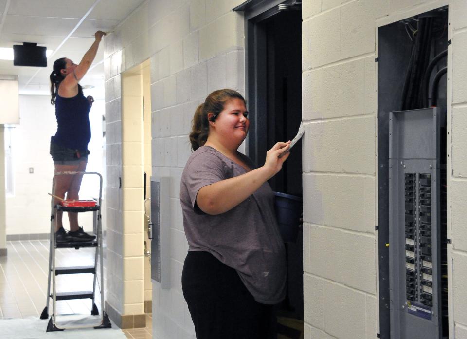 Tami Fitzpatrick, a substitute teacher/summer help, and Grace Sparks, a summer worker, are busy painting a hallway at Norwayne Elementary School.