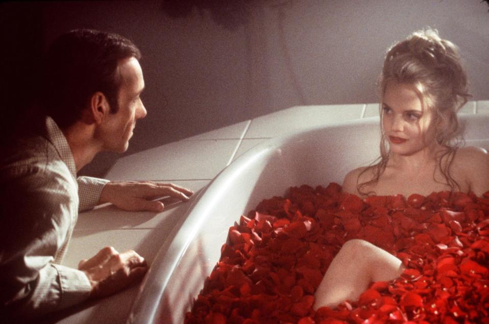 Kevin Spacey looking at Mena Suvari, who is in a bathtub filled with rose petals, in a scene from "American Beauty"