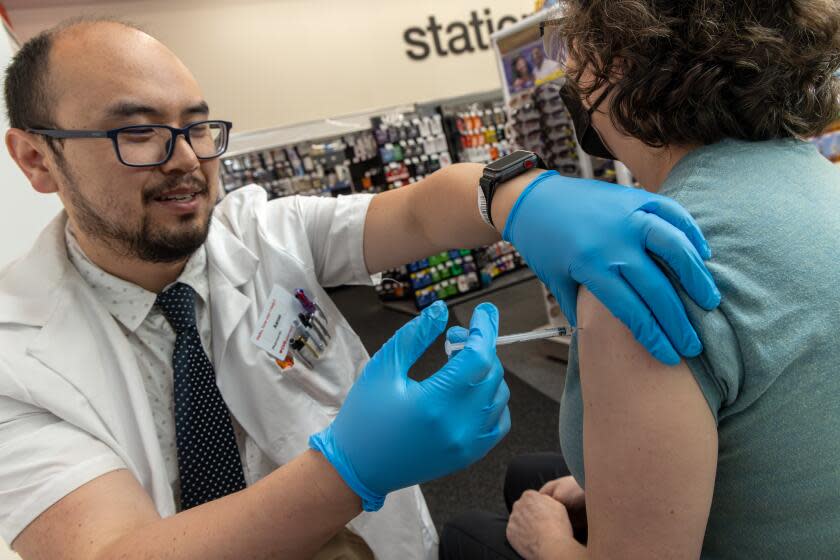 EAGLE ROCK, CA - SEPTEMBER 14: Pharmacist Aaron Sun administers new vaccine COMIRNATY® (COVID-19 Vaccine, mRNA) by Pfizer, to Jennifer Grappone at CVS Pharmacy in Eagle Rock, CA. (Irfan Khan / Los Angeles Times)