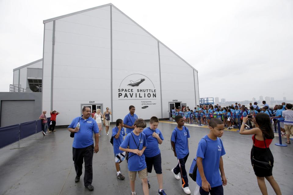 Visitors walk past the newly completed pavilion that houses the space shuttle Enterprise on the deck of the Intrepid Sea, Air & Space Museum in New York, Wednesday, July 10, 2013. With a ribbon-cutting ceremony the pioneering shuttle has been restored from the damages it incurred during Superstorm Sandy. (AP Photo/Seth Wenig)