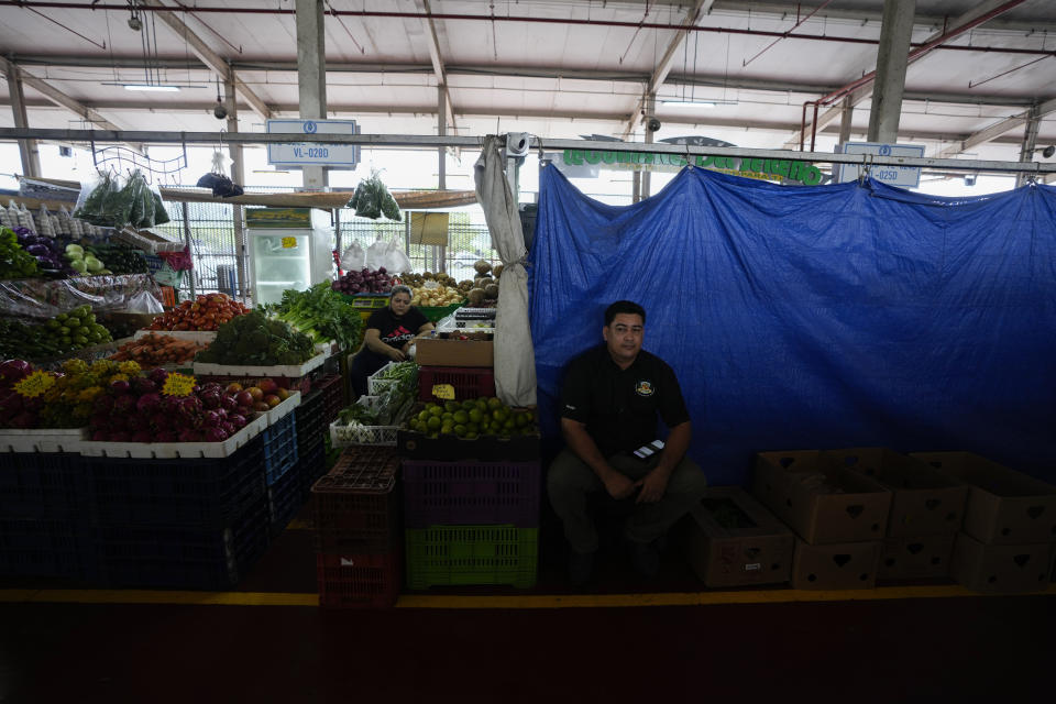 A vendor sits in front of his curtained stall hoping for his produce delivery to arrive at a market in Panama City, Wednesday, July 20, 2022. A third week of protests and highway blockades have begun to impact the supply of food and other items in parts of Panama. (AP Photo/Arnulfo Franco)