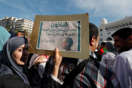 A demonstrator carries a sign as teachers and students take part in a protest demanding immediate political change in Algiers, Algeria March 13, 2019. The sign reads: "The law should be like death, which spares no one". REUTERS/Zohra Bensemra