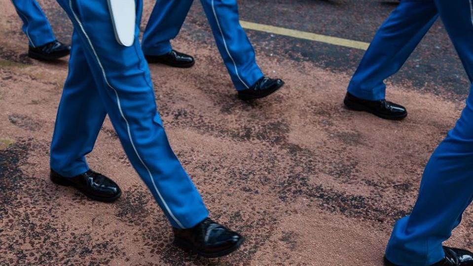 Legs of man in blue trousers and black shoes walking on the road 