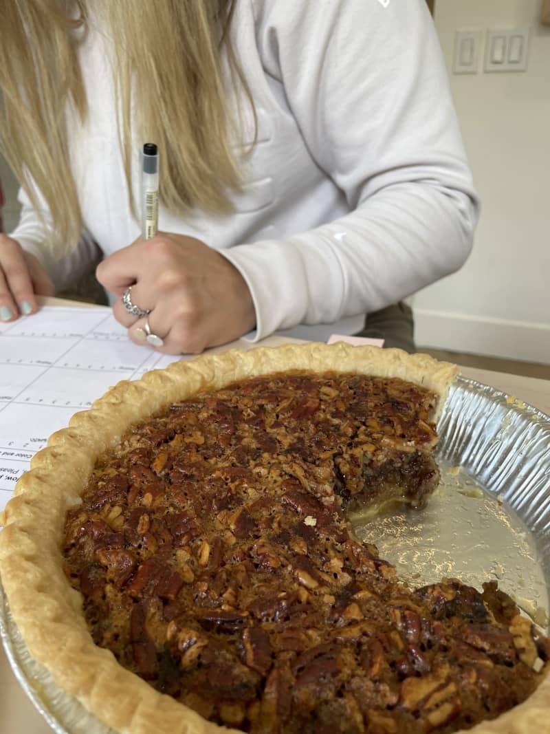 pecan pie with chunk cut out and person filling out test form