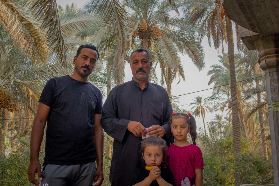 Zemen Al Shammari, left, with his father and daughters. Al Shammari works at the Fedek garden, then returns to his home in a <em>bustaan</em>, a farm with date palms, pomegranates, eggplants, beans, livestock, that serve as a desertification buffer.<span class="copyright">Sam Kimball</span>