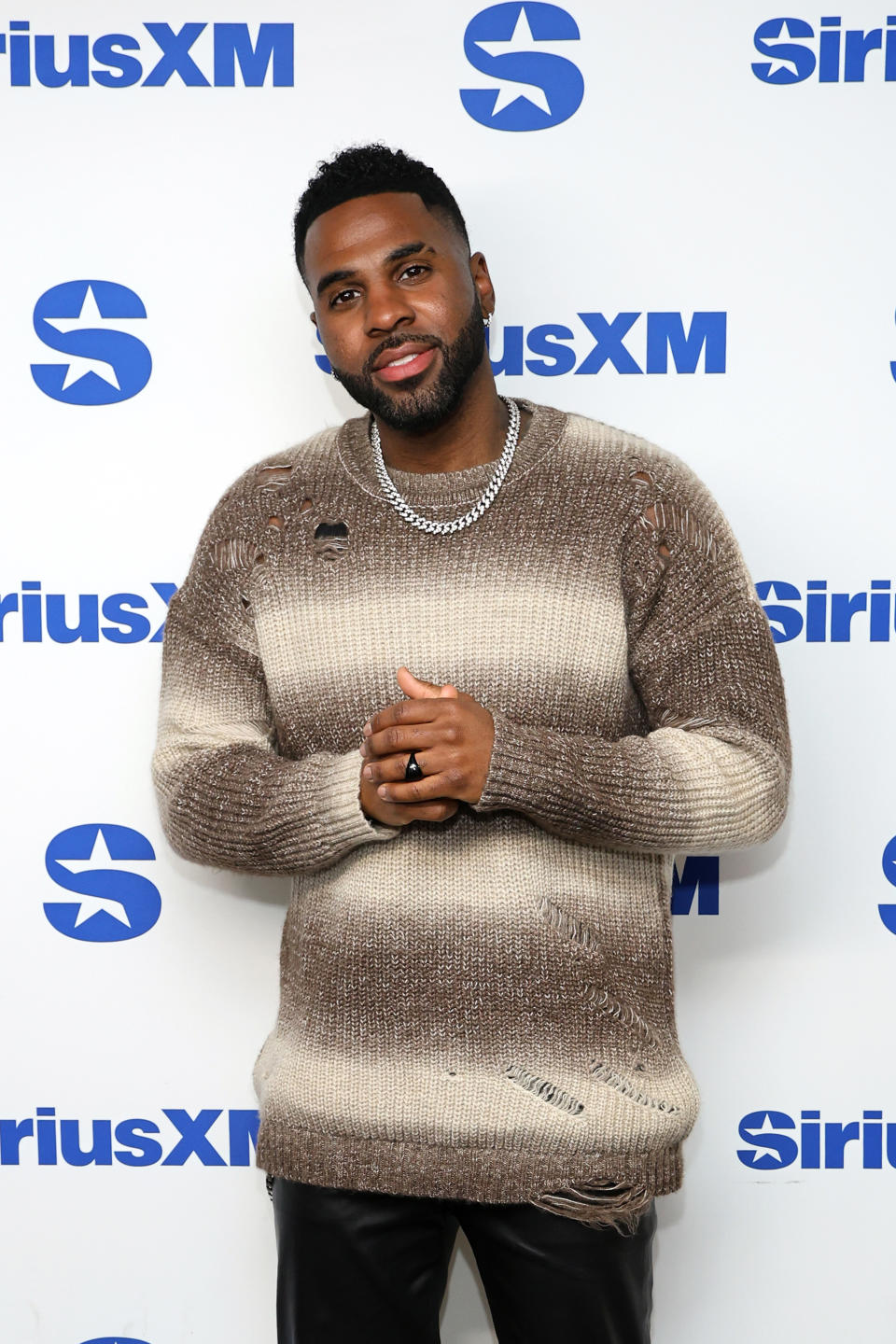 Jason Derulo in a textured sweater posing on the red carpet at a media event