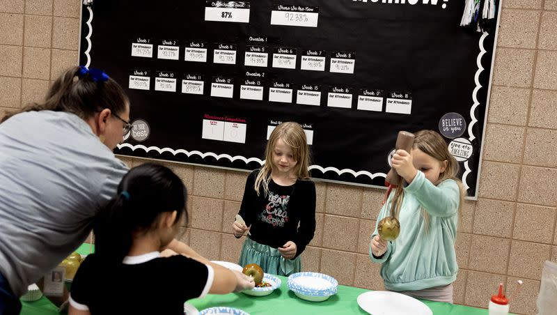 Attendance secretary Heather Lane helps Masina Irons, Jazzmyn Brems and Leda Meek make candy apples that they earned for improving their attendance at Whittier Elementary School in West Valley on Friday, Nov. 3, 2023.
