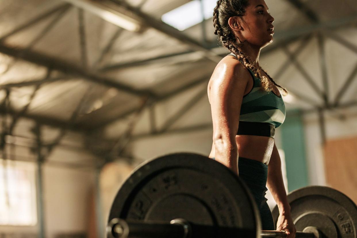 young woman lifting very heavy weights at gym