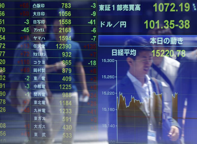 Passersby are reflected in an electronic stock quotation board outside a brokerage in Tokyo July 14, 2014. REUTERS/Issei Kato